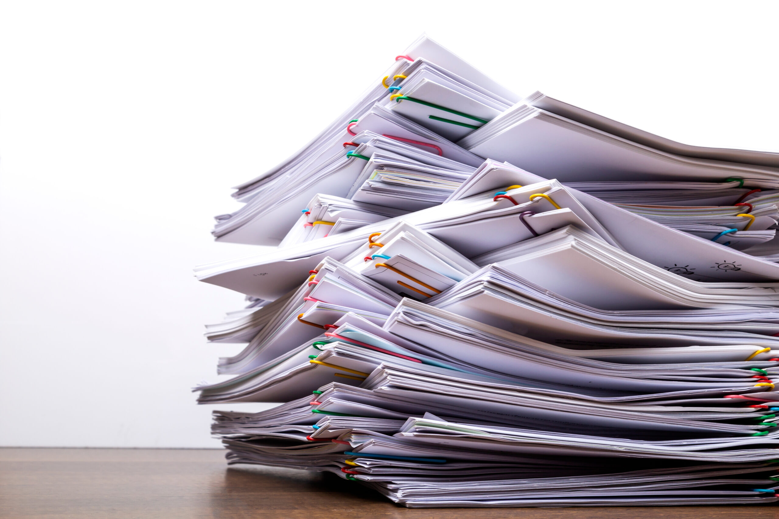 Stack of document paper with colorful paperclip place on wooden table, business concept paperless used and work overload .